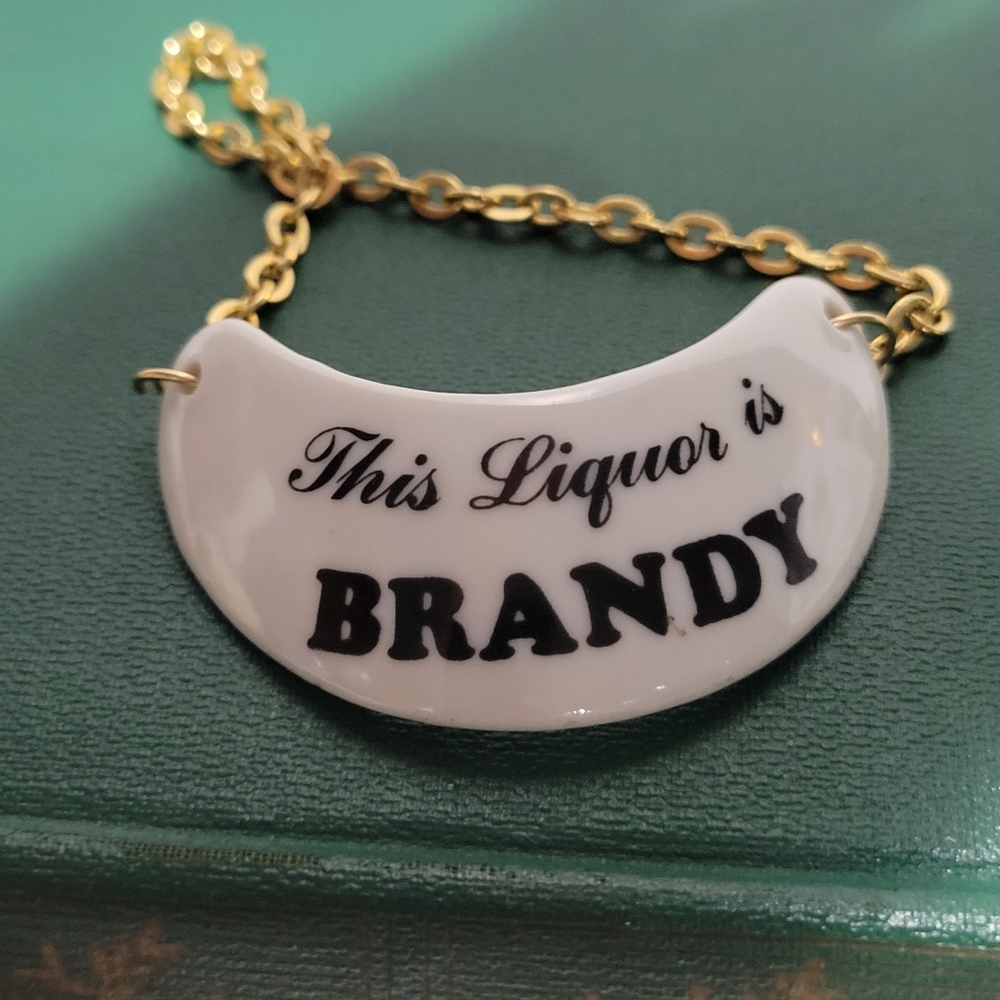 Vintage Porcelain gold tone chain liquor decanter tag This liquor is Brandy